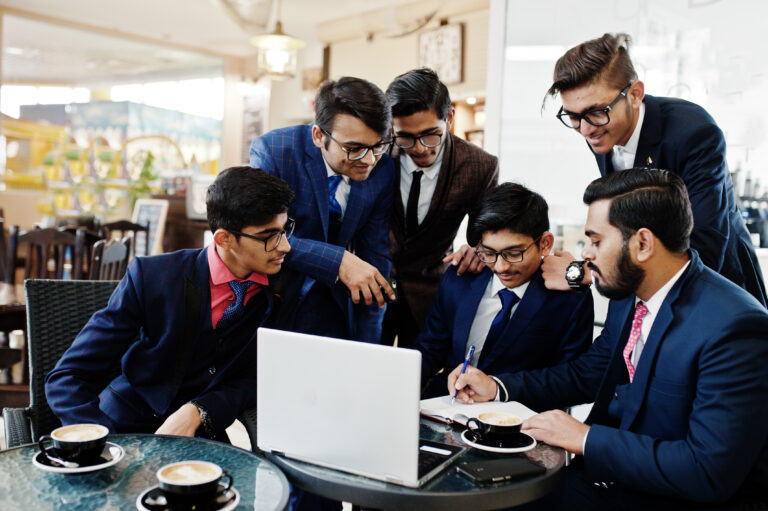 Collaborative process of indian business mans during brainstorming meeting in office.Diverse team of young people dressed in suits cooperating on developing common project.